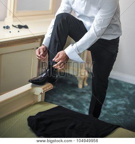 Best man getting ready for a special day. A groom putting on shoes as he gets dressed in formal wear