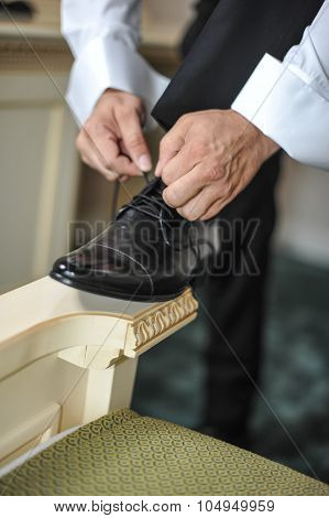 Best man getting ready for a special day. A groom putting on shoes as he gets dressed in formal wear