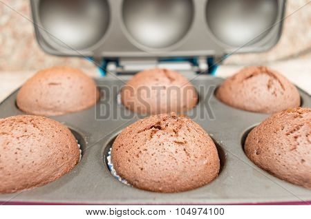 Delicious fresh chocolate cupcakes straight out of oven still sitting inside metal pan, shot from si
