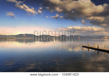 Wooden Pier Or Jetty And On A Blue Lake Sunset And Sky Reflection On Water. Versilia Tuscany, Italy
