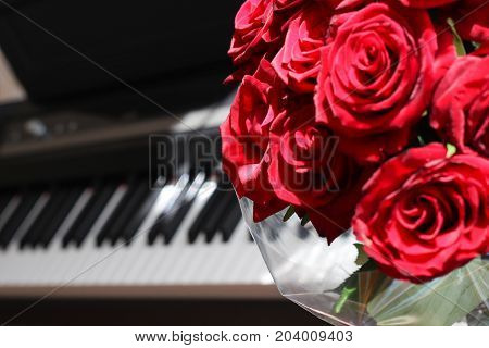 The bouquet of red roses on the background of a piano