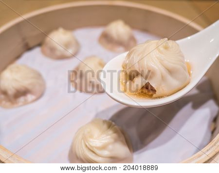 Closeup of Xiao Long Bao with soup in the spoon Streamed Pork Dumplings Taiwan food (Selective Focus)