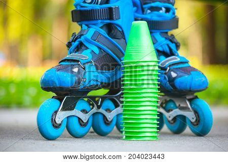 Close up of blue roller skates with slalom cones lying on asphalt.