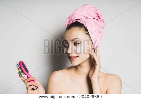 Young woman with gel patches under the eyes looks at herself in the mirror.Towel on the head