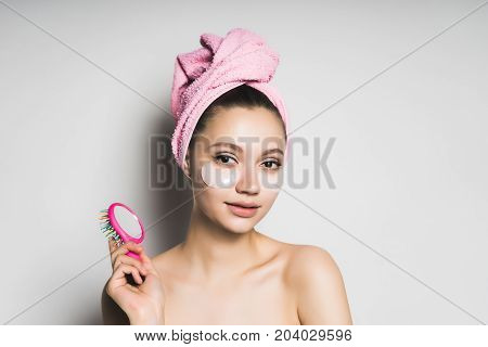 A girl with a mask under her eyes and a comb for her hair in her hand. Healthy face and hair