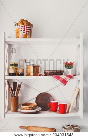 White wooden shelf - kitchen furniture in rustic style with utensils and bright decorative details