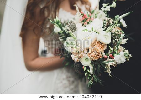 Beauty wedding bouquet with different flowers in hands.