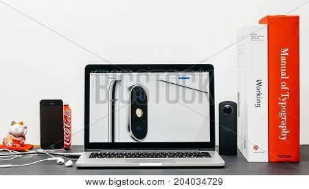 PARIS FRANCE - SEP 3 2017: Minimalist creative room table with Safari Browser open on MacPook Pro laptop showcasing Apple Computers website with latest iPhone X 10 with camera close-up
