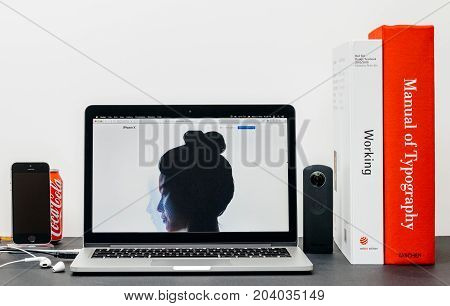 PARIS FRANCE - SEP 3 2017: Minimalist creative room table with Safari Browser open on MacPook Pro laptop showcasing Apple Computers website with latest iPhone X 10 with