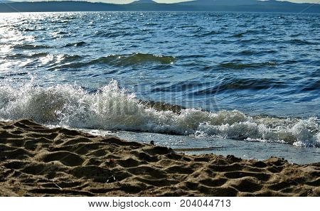noisy wave is incident on the shore of the lake, fly spray around, South Ural, Uvildy