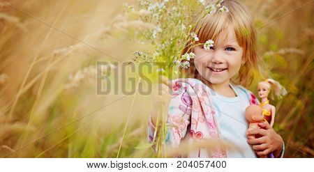 Adorable little girl playing in the wheat field on a warm summer day