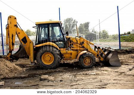 yellow excavator stands on the construction site