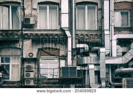 Aluminum ventilation pipes outside the old Industrial building of the factory, remade inside in a modern office. Tinted vintage background for modern themes