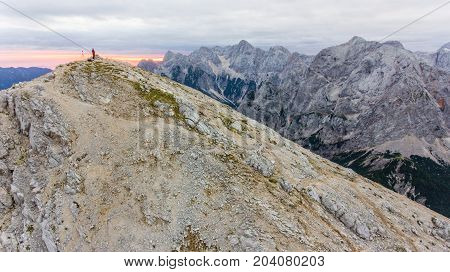 Lonely hiker on mountain top at dawn. Mojstrovka in Julian Alps, Slovenia.