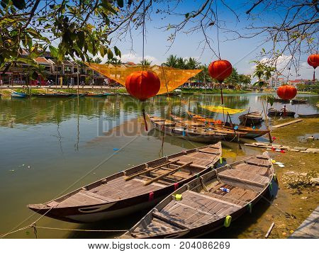 HOIAN, VIETNAM, SEPTEMBER, 04 2017: Traditional boats in front of ancient architecture with red lanterns in Hoi An, Vietnam. Hoi An is the World's Cultural heritage site, famous for mixed cultures architecture.