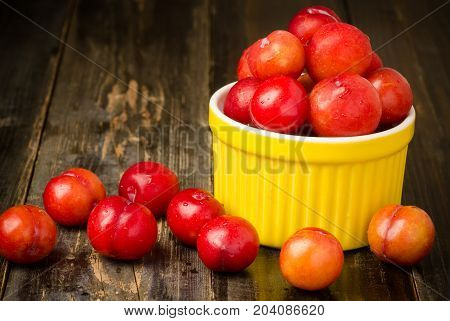 Plum Julee fruit in a yellow bowl on wooden background,healthy fruit