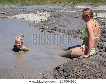 Mother gently bathing my daughter in the mud. Treatment non-traditional methods.