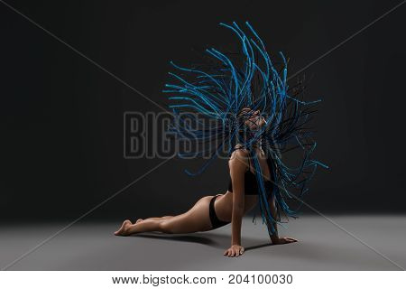 Brunette with blue dreadlocks wearing black lingerie against black wall