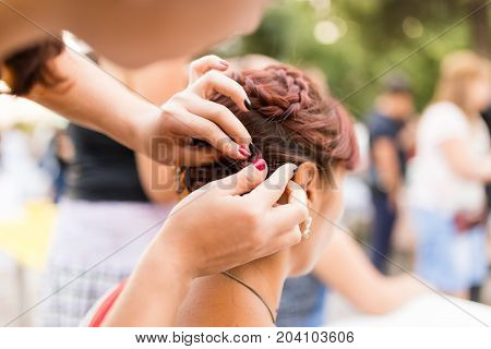 the stylist weaves the female braids on the head .