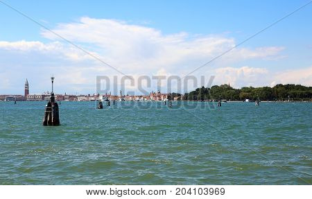 VENICE island in Italy by boat in the middle of the sea. You can see the bell tower of St. Mark's Basilica
