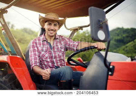 Farmer driving tractor in the fields during harvest in countryside. worker sitting on his tractor smiling.