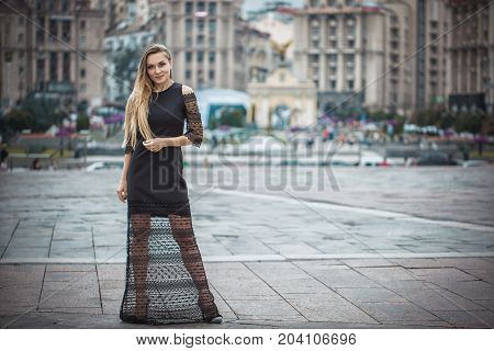 Blonde wooman dreesed in black dress in the city. Rainy day. Autumn in Kyiv