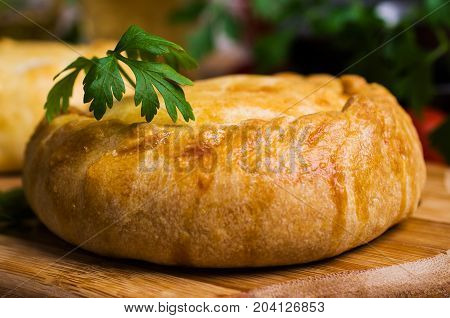 Round meat pie with vegetables and spices on a wooden background. Selective focus.