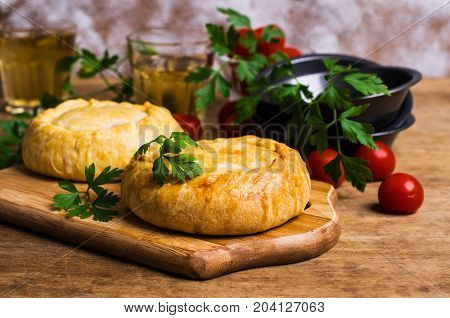 Round meat pie with vegetables and spices on a wooden background. Selective focus.