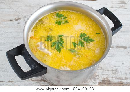 Creamy soup with fish fillet and mussels in a pot on a wooden background. Healthy eating concept. Mediterranean lifestyle.