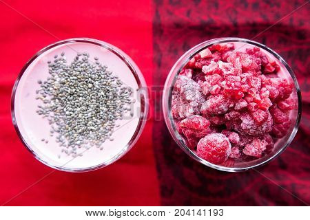 Chia and frozen raspberies cottage cheese breakfast in two small transparent glasses