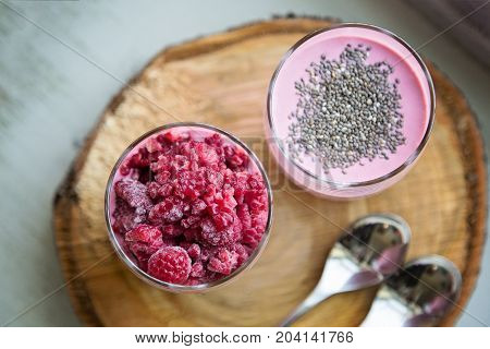 Chia and frozen raspberies cottage cheese breakfast in two small transparent glasses