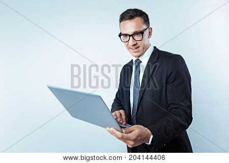 Looking interesting. Waist up shot of a concentrated male businessman focusing his attention on a screen of his computer while reading something interesting over the background.