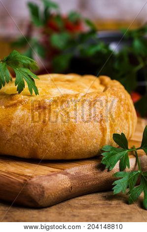 Round meat pie with vegetables and spices on a wooden background. Selective focus.