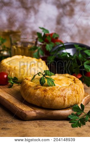 Round meat pie with vegetables and spices on a wooden background. Selective focus.