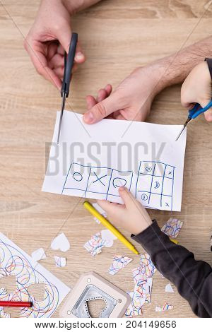 father and son hands cutting paper with scisors view from above