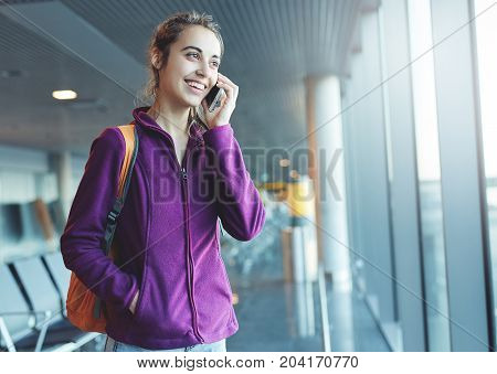 Girl at the airport window talking by phone
