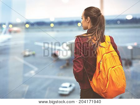 Girl at the airport window looking outside