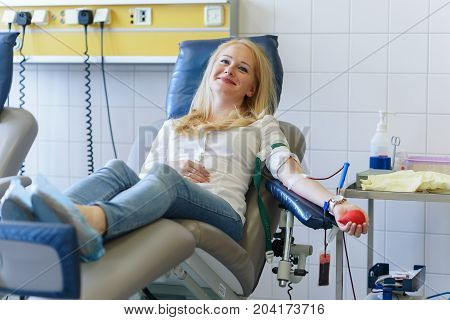 Young Caucasian Woman With Toy Heart In The Hand Donates Blood For Saving Lives And Medical Research
