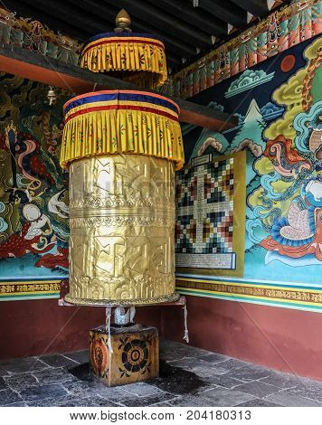 Wall paintings and large prayer wheel inside the portico of the Punakha Dzong dating from 1637 Punakha Bhutan Asia