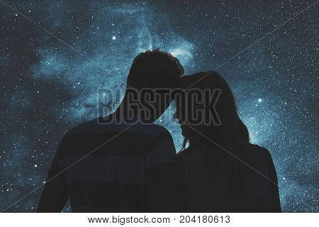 Silhouettes of a young couple under the starry sky.