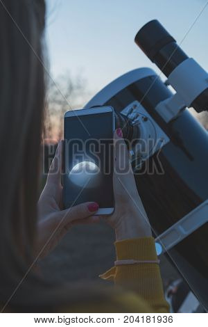 Photographing the Moon through a telescope with cellphone.