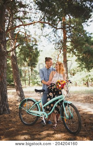 Image of love story in the forest. Beautifull couple kissing and embracing near the shore of a mountain river with decorated table. Girl smiling in the arms.