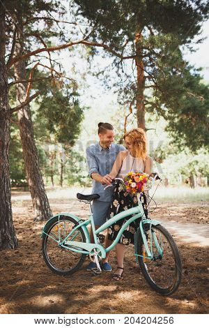 Image of love story in the forest. Beautifull couple kissing and embracing near the shore of a mountain river with decorated table. Girl smiling in the arms.