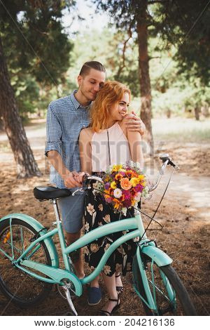 Image of love story in the forest. Beautifull couple kissing and embracing near the shore of a mountain river with decorated table. Girl smiling in the arms.