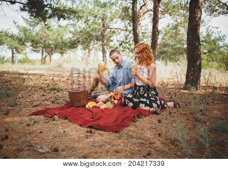 Image of female and manle with bright picnic, sitting in the forest. Lifestyle concept.