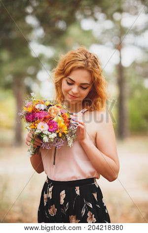 Close-up portrait photo of happy woman with colorful flowers in the forest. Lifestyle and romantic concept.
