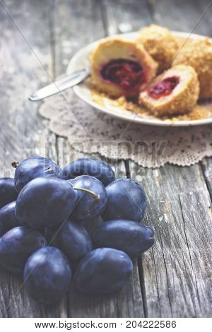 Plums and plum dumplings on wooden background