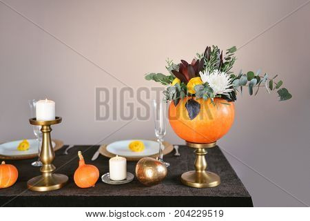 Beautiful autumn floral bouquet in a pumpkin vase. Preparing for Halloween. Table setting for the wedding