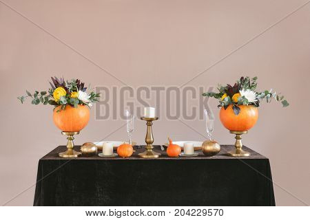 Beautiful autumn floral bouquet in a pumpkin vase. Preparing for Halloween. Table setting for the wedding