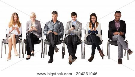 Group Of Multi Ethnic Business People Sitting On Chair Using Cell Phone Against White Background
